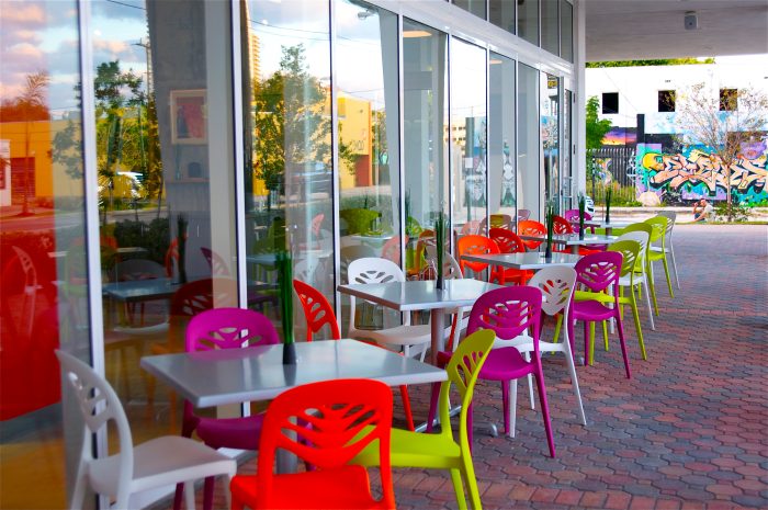 Colorful outdoor seating area at Jimmy'z Kitchen Wynwood Restaurant in Miami, with graffiti walls in background