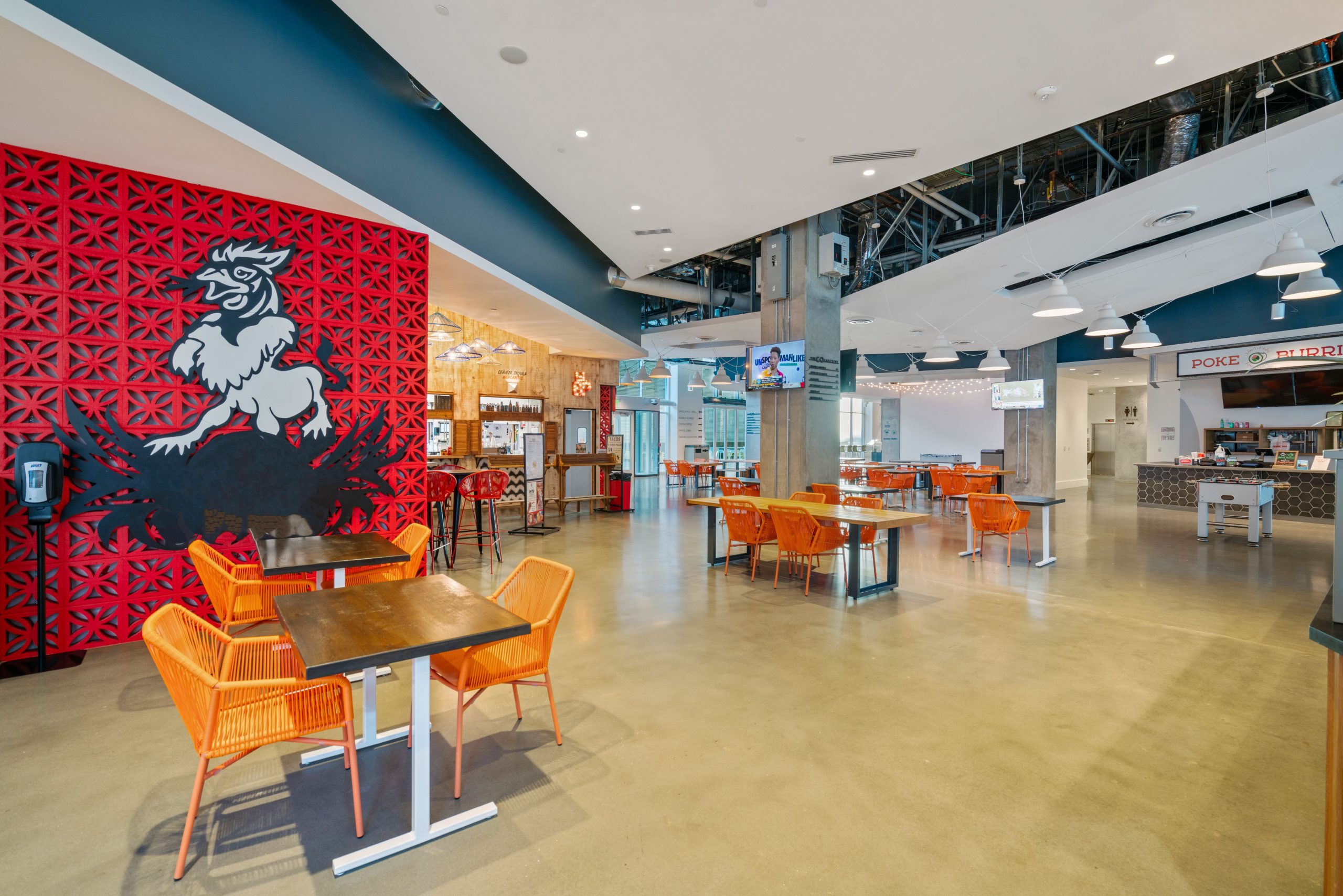 Restaurant logo in bright modern Food Hall with orange chairs in an open modern space.