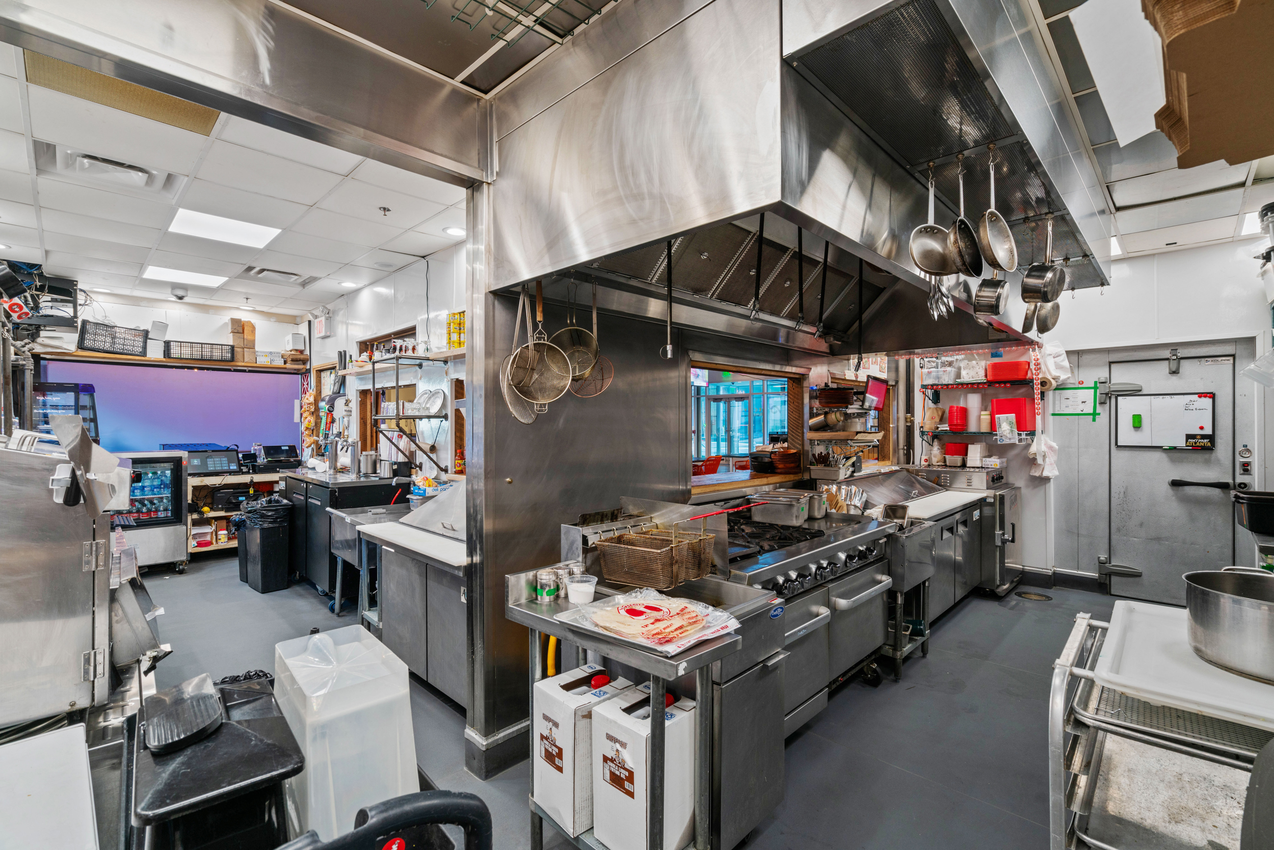 Commecial kitchen with 10 foot hood, fryer, stove, refrigerator and walk in cooler.