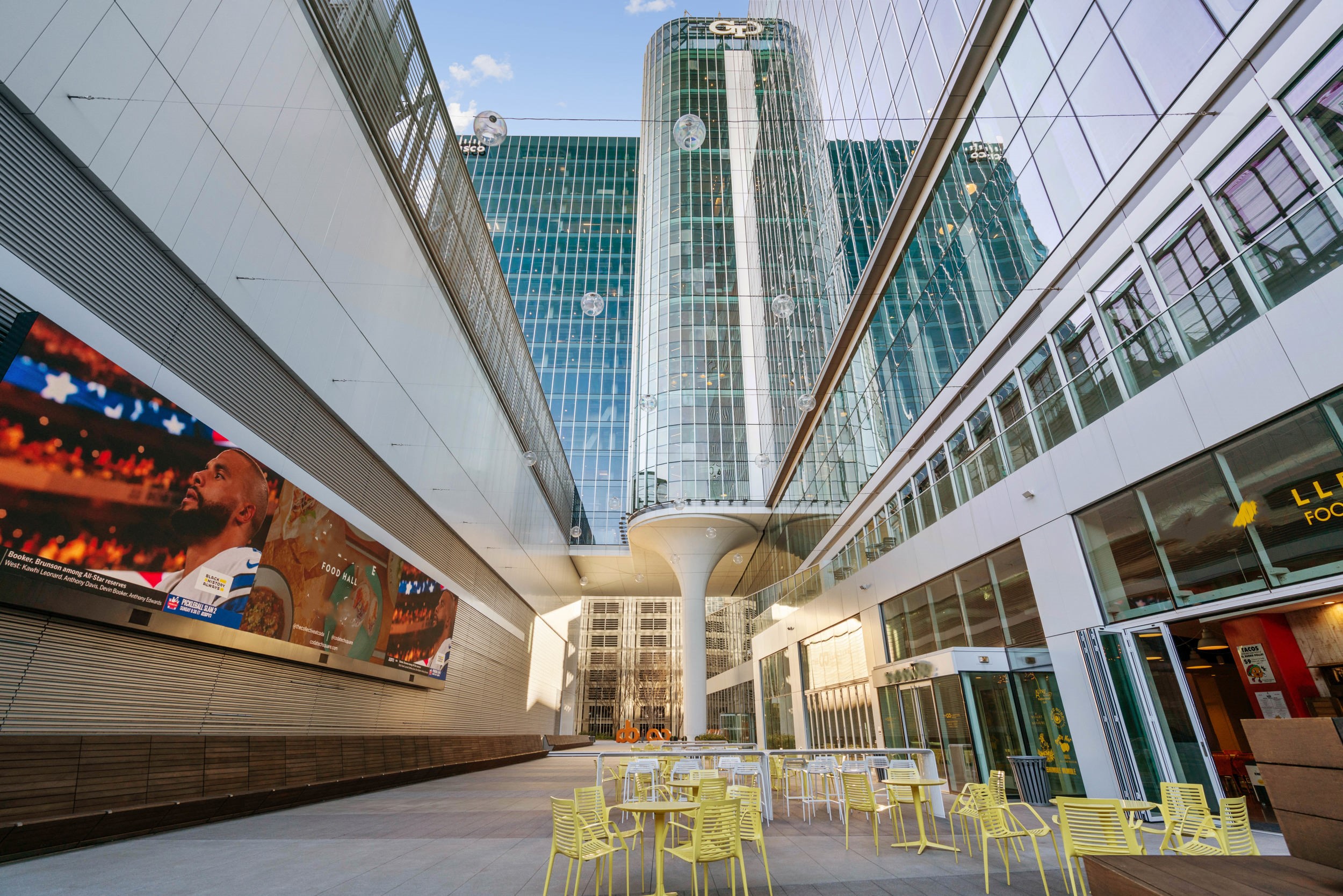 Outdoor seating area located in ultra modern Atlanta Midtown building with giant screen, colorful chairs and tables