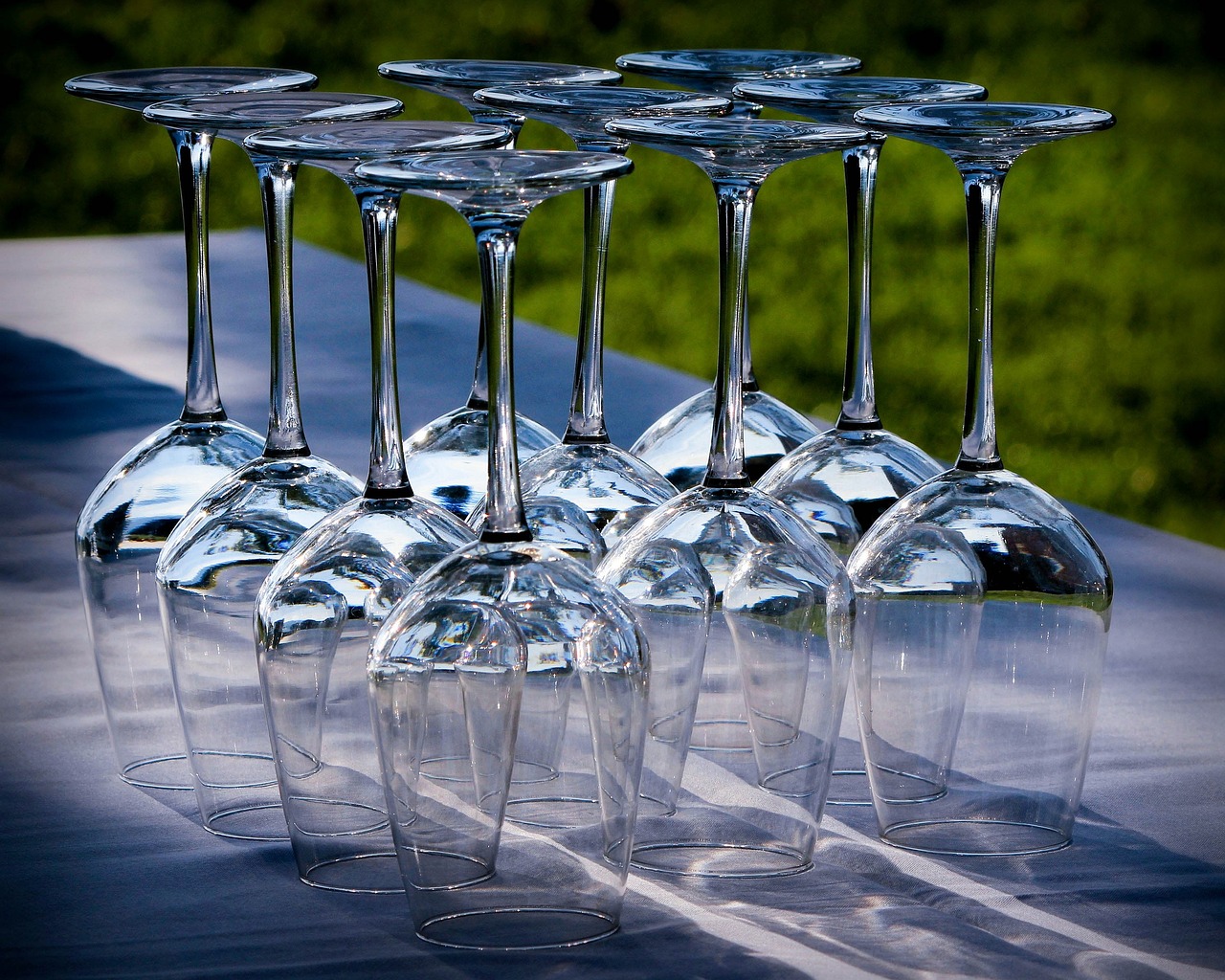 Crystal clear polished white wine glasses placed upside down on a outdoor table.