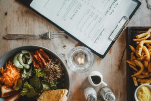 Restaurant table with menu, food and salt & pepper shakers.