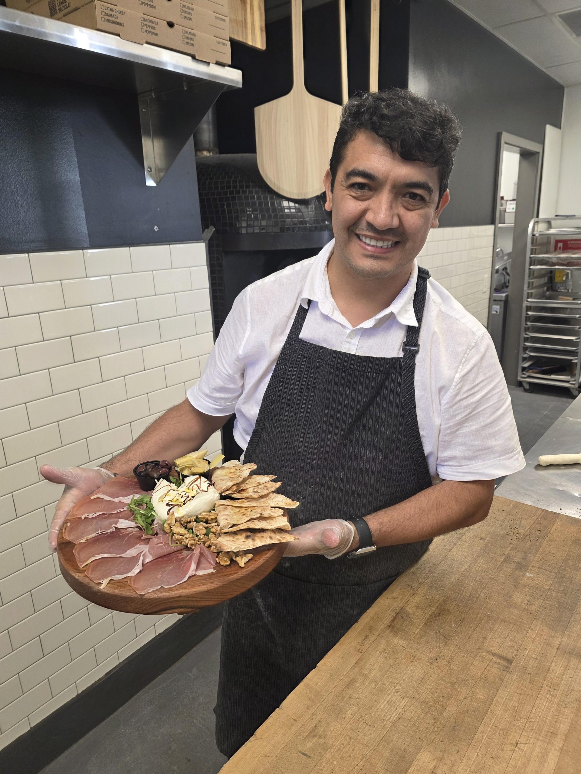Chef John Frank Cely presenting a charcuterie board at Char Pizzeria Halcyon, represented by Jimmy Carey Commercial Real Estate, Atlanta’s Premier Restaurant Broker specializing in Restaurant Tenant Representation Atlanta.